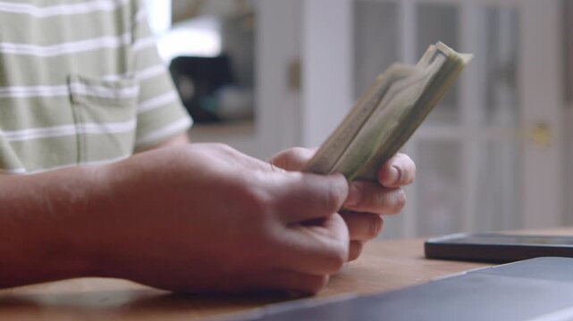 Hands carefully sort and count cash at a warm, inviting desk, revealing the simple yet meaningful moments in daily financial management