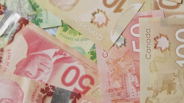 A stunning collection of Canadian banknotes showcasing their vivid hues and detailed patterns fills the frame, highlighting the artistry of currency