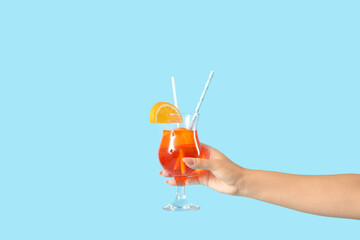 Obraz premium Young woman with aperol spritz cocktail on blue background