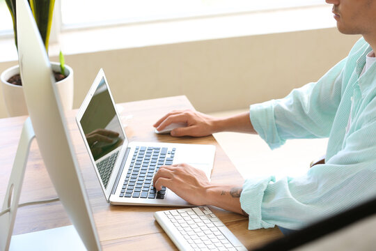 Male programmer working with laptop at table in office, closeup