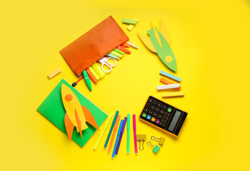Naklejka premium Frame made of paper rockets, calculator and different stationery on yellow background