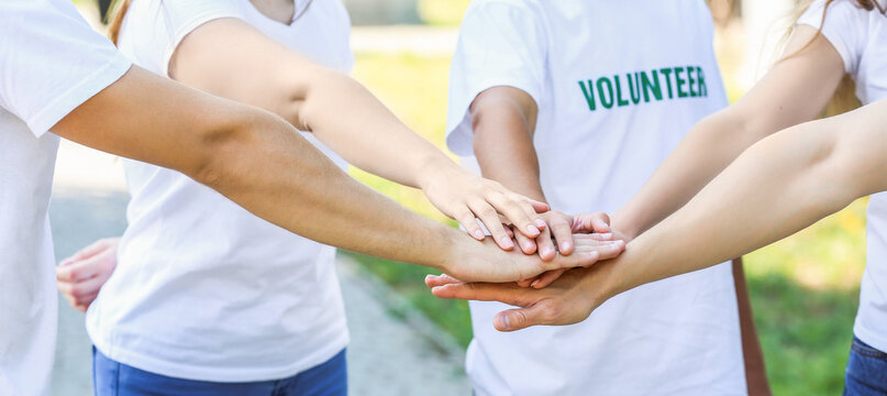 Group of volunteers putting hands together outdoors
