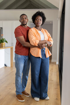 African American couple standing, embracing in center of modern open-plan kitchen with island plant