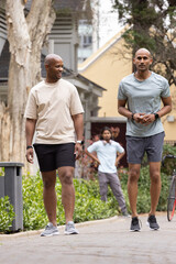 Obraz premium African American men walking together on paved path wearing athletic clothes, watches, headphones