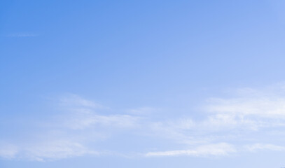 Fototapeta premium Blue sky background with soft white clouds and clear atmosphere. Natural cloudscape texture for weather, summer, nature, travel, banner, wallpaper, advertising and graphic design projects.