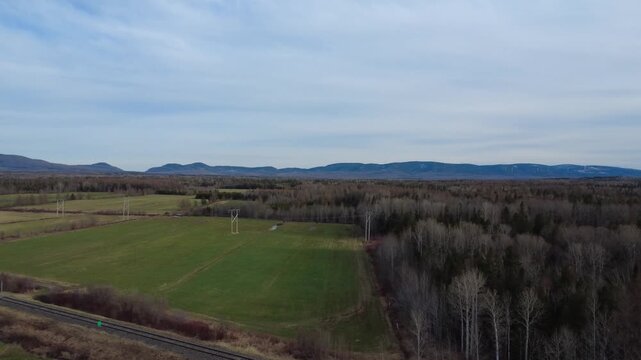 Aerial drone footage of green fields, forests, and high-voltage power lines crossing the scenic Matapedia Valley beneath the Appalachian Mountains.