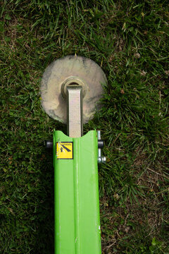 Outrigger arm and pressure plate of a hydraulic lift on a grassy surface.