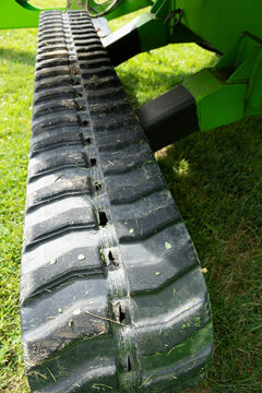 Close-up of textured, pattern of a track system with dirt and grass on a hydraulic lift