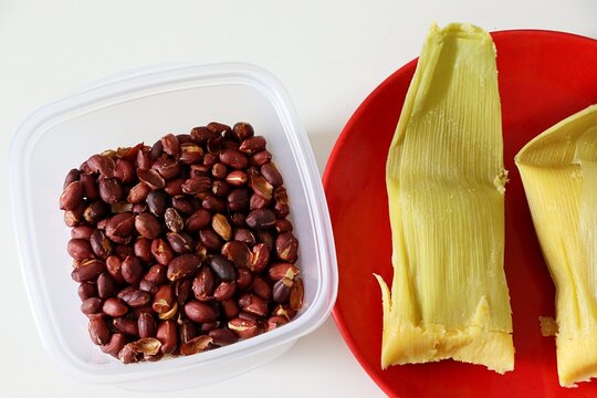 Traditional Brazilian pamonha wrapped in corn husks served alongside roasted peanuts. Concept of Sao Joao festival in Brazil. 