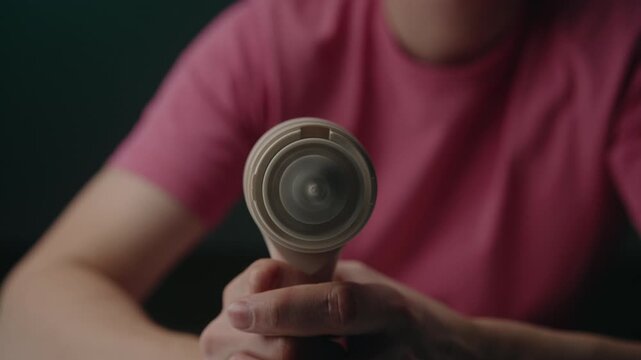 Close-up of person holding electric lint remover and turning it on, with sharp blades inside spinning rapidly, preparing device for cleaning clothes and restoring fabric. Shooting in slow motion.