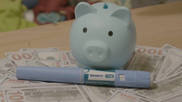 07.October 2025 - Qawra, Malta - Piggy Bank with Ozempic Injection Pen on Banknotes Editorial. High quality photo