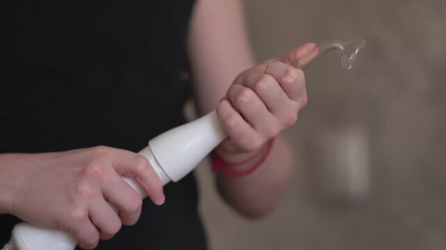 A teenager uses a Darsonval device, switching the attachment. Professional skincare at home. Teenage skin issues during hormonal changes. High quality FullHD footage