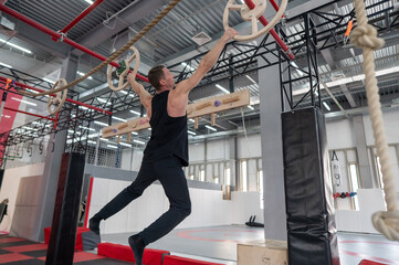 An athletic man practices at a ninja club's indoor obstacle course. © Михаил Решетников