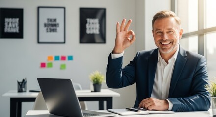 Fototapeta premium Smiling businessman giving OK gesture in modern office with natural light, perfect for business success and approval