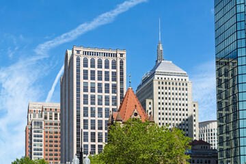 Obraz premium Architectural contrast featuring the historic Trinity Church tower and modern Boston skyscrapers in Copley Square 