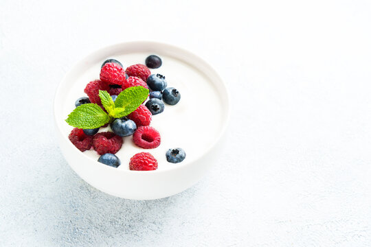 Yogurt with fresh berries in white bowl. Healthy snack or breakfast. Diet food.