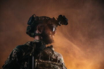 Close up military operator with advanced night vision gear against warm smoky background, modern combat technology © Валерия Стоганенко