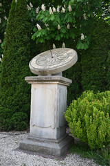 Antique stone sundial monument standing in a beautiful spring garden © Viktoriia Kolosova