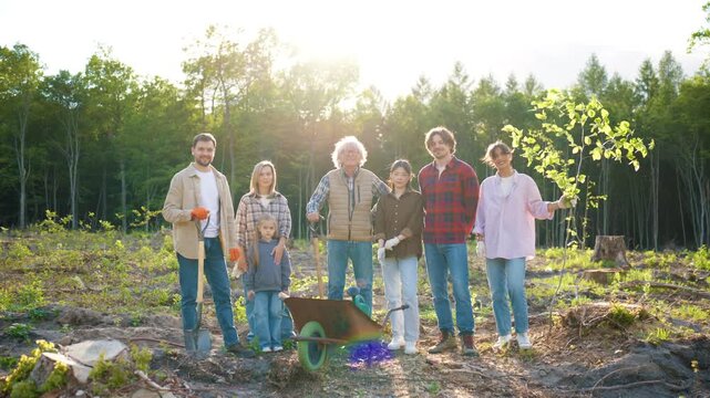 Eco volunteer group standing after tree planting activity. Diverse people looking at camera and showing teamwork. Community members supporting eco conservation and forest renewal. Sustainable future.