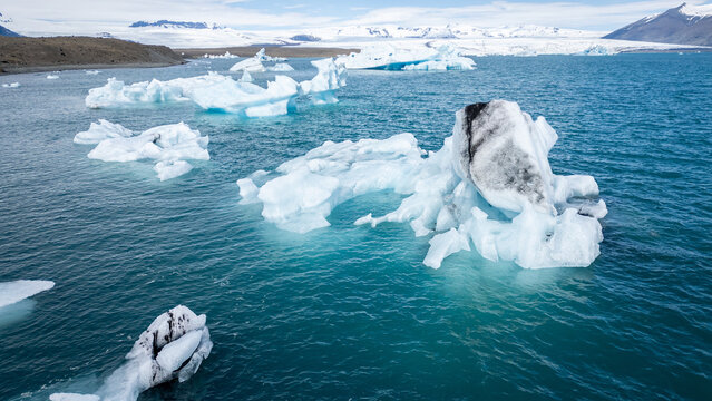 Des icebergs sur une mer bleu devant un glacier