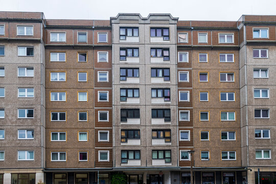 Berlin, Germany, May 2, 2026. High rise residential apartment block with a weathered concrete and brown tiled facade under a gray sky.