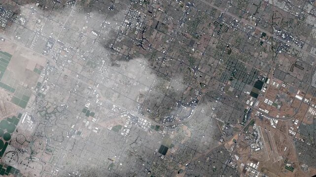 Rotating aerial view of Phoenix urban grid and desert landscape with passing clouds satellite view from space based on Nasa imagery