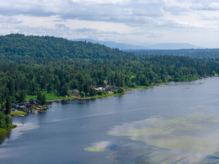 Fototapeta premium Aerial View Of Forested Hills And Waterfront Homes Along A Calm Lake Near Mission BC Canada