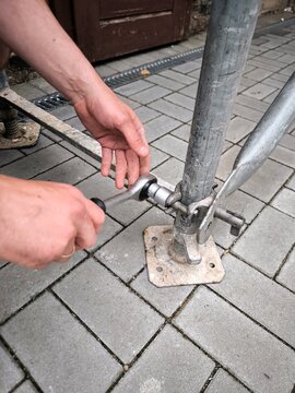 Workers are tightening the fasteners of metal scaffolding with a wrench.
