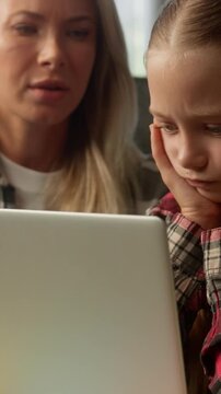 Stressed Caucasian child little girl mom studying problem laptop difficult task sad family kid schoolgirl daughter pupil learner upset remote learning failure at home parent woman female mother help