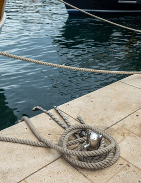 Close-up of mooring lines securing a luxury yacht at a marina. Nautical infrastructure, recreational boating, coastal travel, marine transportation and waterfront tourism concept
