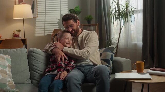Caucasian happy family dad male girl daughter relaxing on couch at home hugging parent kid father in living room man touching nose of child cuddling love relationship custody adopt childcare bonding