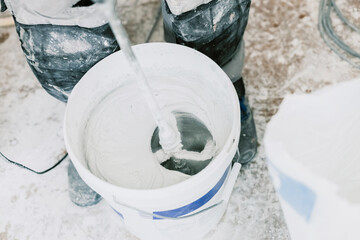A young man beats putty with a construction mixer. © Nataliya