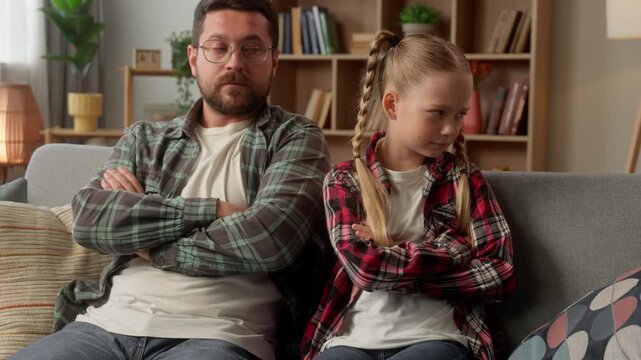 Frustrated Caucasian dad family conflict daughter arguing at home crossing arms parent male talking guy offended child father kid turning away little girl man avoid trouble psychology quarrel indoors