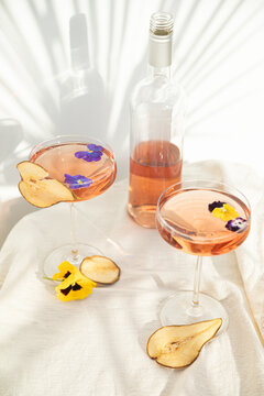 Tropical rose wine glasses with summer cocktails with leaves shadow