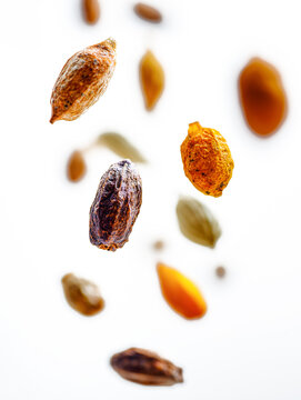 Levitating and falling terminalia chebula haritaki and almond nuts with traditional ayurvedic herbs isolated on bright white background