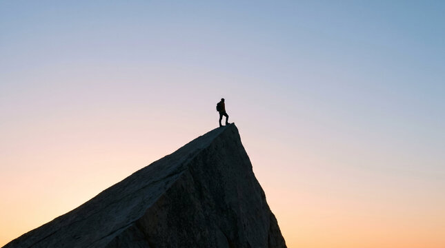 Lone explorer with reflective mood standing on sharp peak representing accomplishment against vast twilight sky with copy space