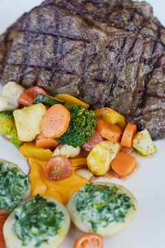 Grilled steak with roasted vegetables and creamed spinach potatoes on plate
