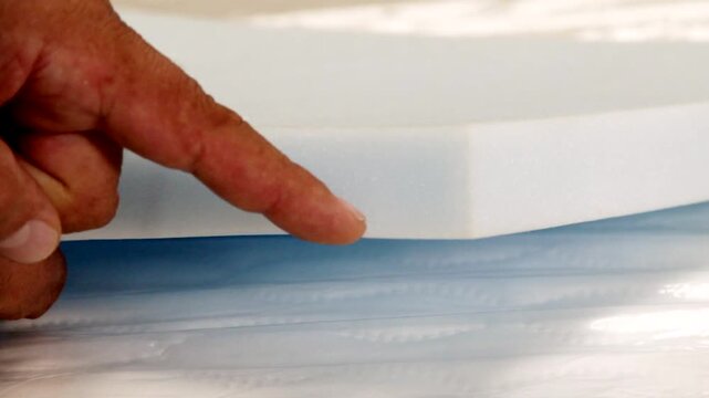 Finger Pointing to Foam Sample Thickness and Density in Close Up.. Close Up of Finger Demonstrating Foam Density and Thickness. Foam Quality Inspection and Material Evaluation. Finger Pointing at Foam