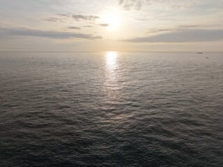 Obraz premium Aerial view of the ocean with sunset reflecting on the water.