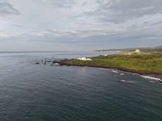 Fototapeta premium Aerial view of a lighthouse on a rocky coastal cape.