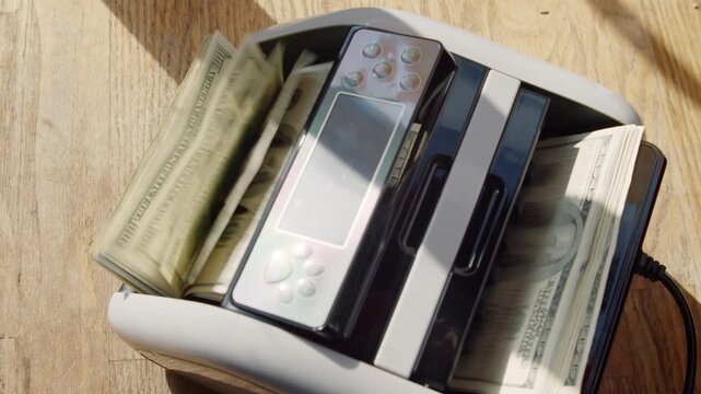 A hand places colorful bills into an unusual toaster, transforming a simple appliance into a quirky work of art that adds charm to the warm kitchen setting