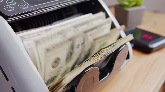 Experience the smooth operation of a money counting machine sorting crisp bills with ease in a modern office setting. Watch the magic of currency counting unfold