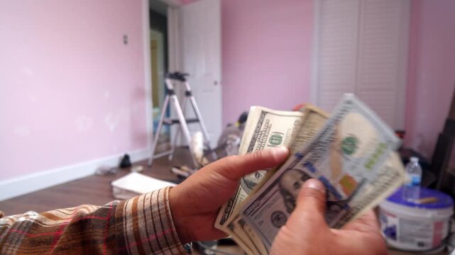 A man carefully counts dollar bills, deciding how much to spend on essential materials for his home renovation. Excitement fills the air as dreams take shape