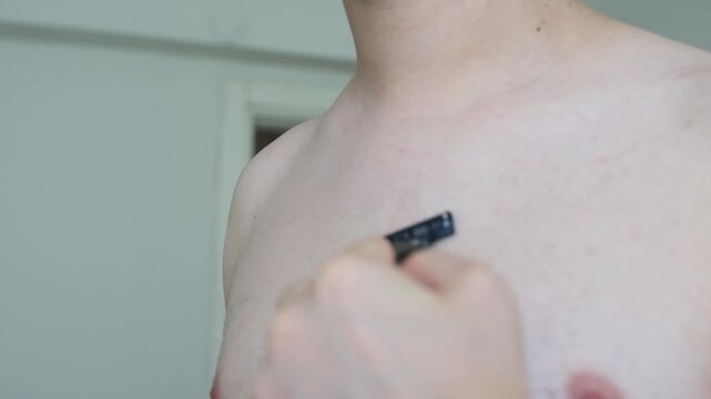 Close-up of man shaving his chest hair with razor blade in bathroom