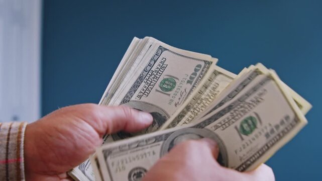 A man carefully counts dollar bills, determining how much he needs to spend on materials for home repairs. Financial planning meets construction needs