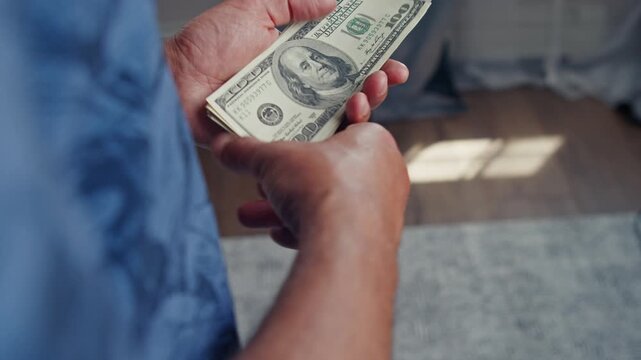 Hands skillfully count fresh banknotes under warm sunlight, capturing the moment of financial excitement in a peaceful indoor environment