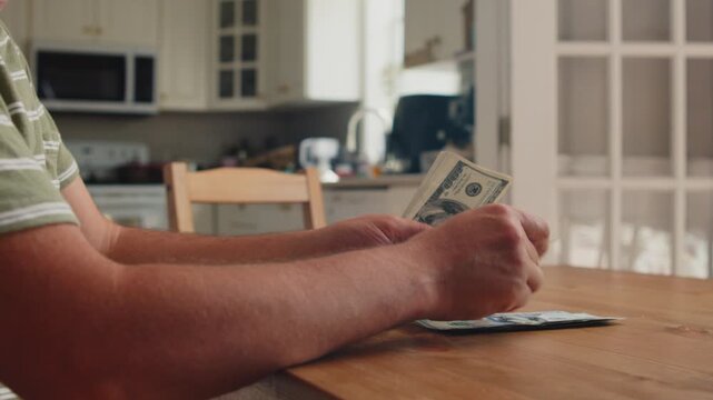Hands carefully count cash at a rustic wooden table in a warm, inviting kitchen, filled with sunlight and homey vibes. Thoughts of tomorrow dance in the air
