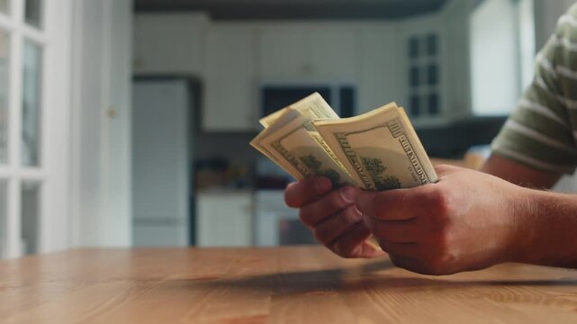 Hands carefully count dollar bills in a cheerful kitchen filled with sunlight. The atmosphere feels warm and inviting, perfect for financial planning
