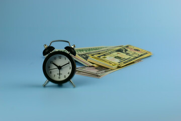 Silver alarm clock stands beside folded bills © Nazir