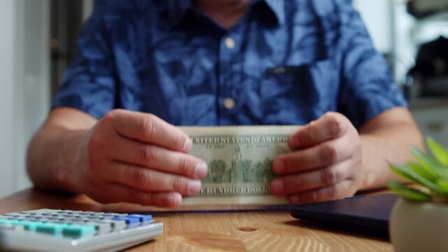 Hands gently count stacks of cash in a bright, inviting space filled with plants. Each note unfolds a story of effort and dedication in this tranquil setting
